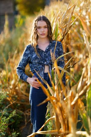 A beautiful portrait of a young woman in a cornfield during a stunning sunset scene