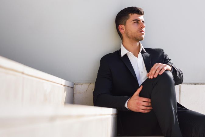 Man in suit resting on wall outside
