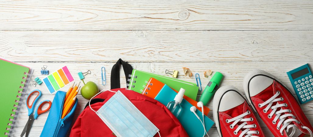 School supplies with medical mask and sanitizer on wooden background