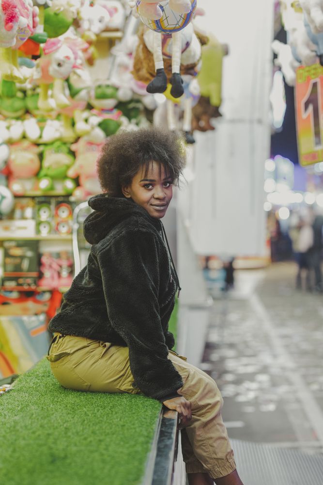 Black female sitting on stall with toys