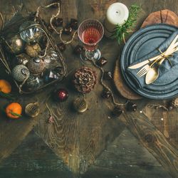 Top view of table setting with crystal flute, pinecone, and candle, square crop with copy space