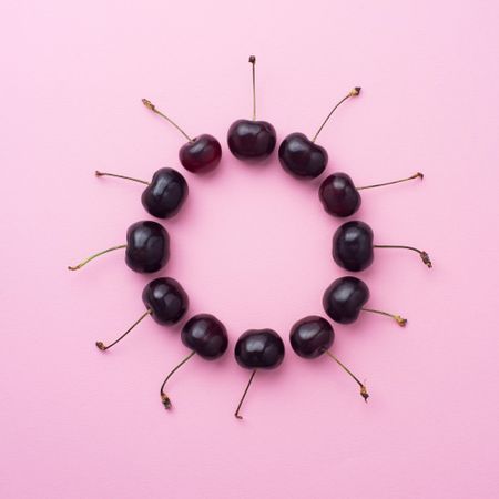 Cherries in a circle shape on pink background