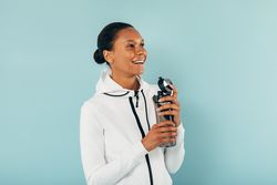 Smiling fit Black woman with water bottle on blue background
