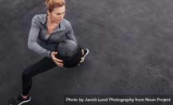 Sportswoman stretching outdoors with medicine ball 0PjkVg
