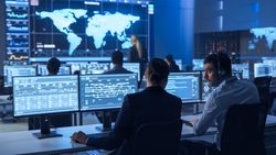Diverse Team Monitors Global Data on Multiple Screens in a High-tech Control Room