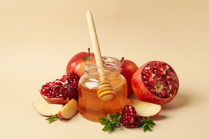 Beige room with pot of honey, open pomegranate and apple