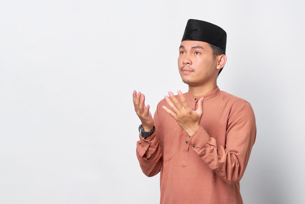 Muslim man in kufi head wear looking up and praying
