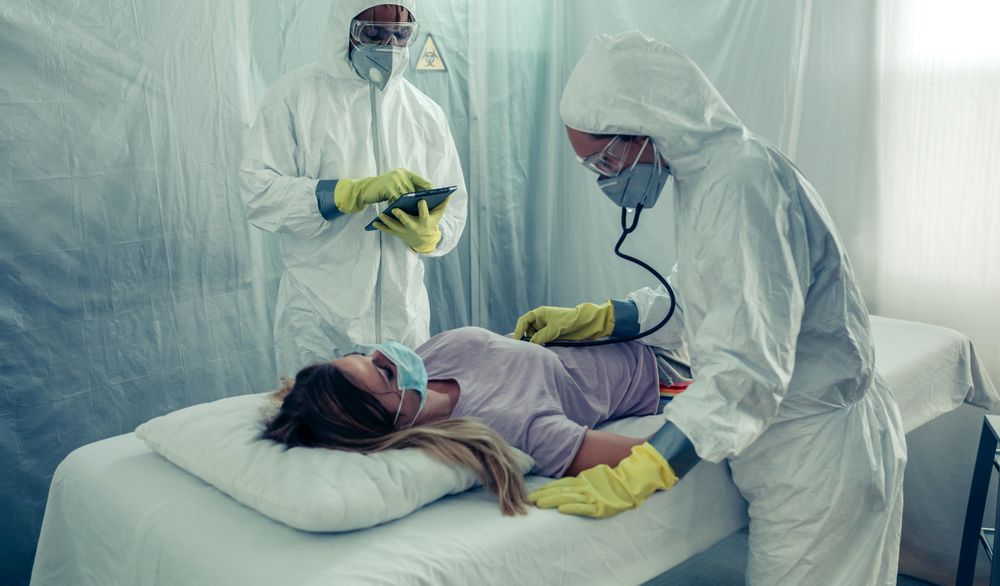 Doctors with bacteriological protection suits attending a patient