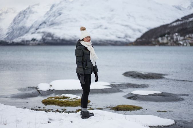 Young asian woman on pond shore against highland in winter