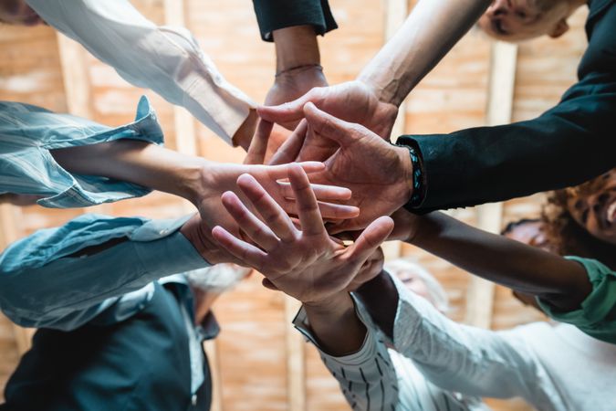 Group of businesspeople joining hands together standing in circle, closeup view from bottom