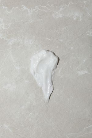 Cream drop on gray background, top view
