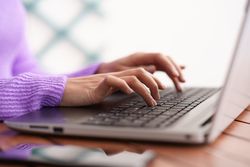 Hands of female typing on laptop keyboard