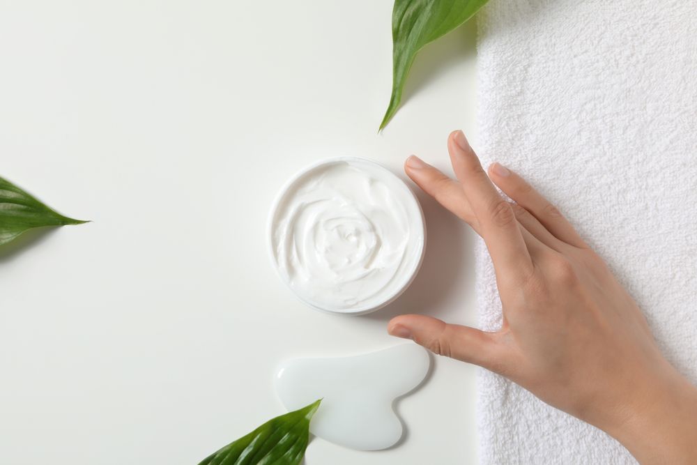A jar of hand cream with leaves on a light background.