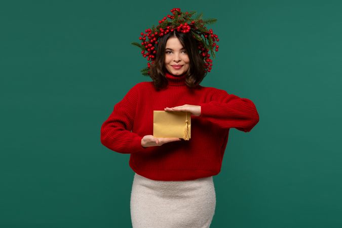 Woman in red sweater presenting golden envelope with tassel