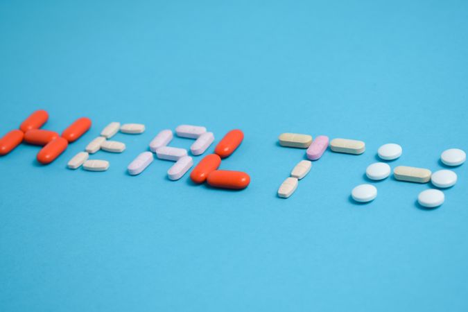 Various pills spelling the word "HEALTH" on blue table