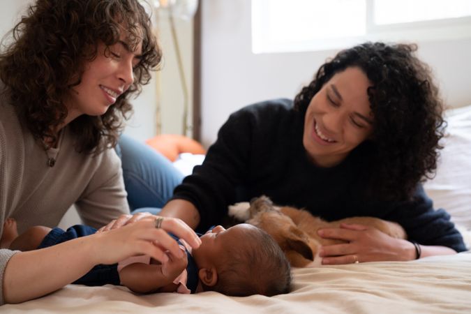 Two women looking down at infant on bed