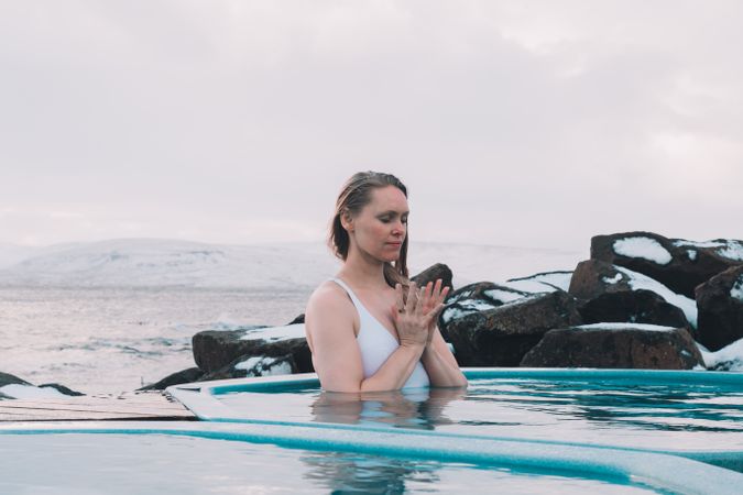 Woman sitting in pool near stones