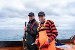 Fishermen looking at camera working on a lobster fishing boat