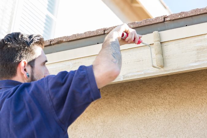 Professional Painter Using Small Roller to Paint House Fascia