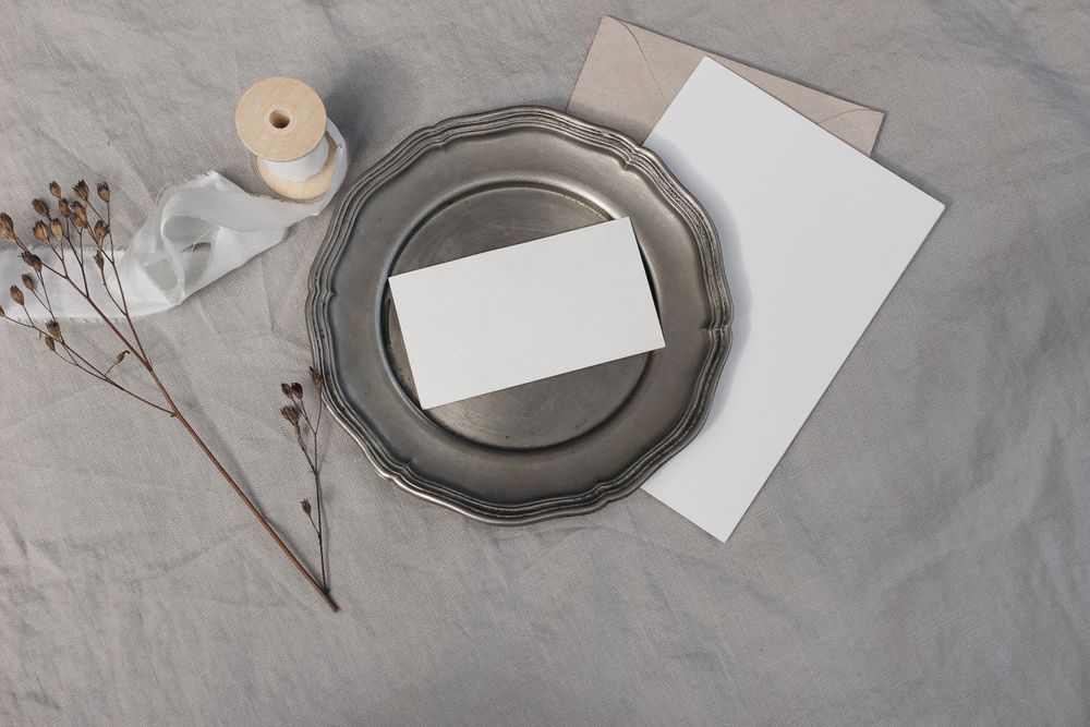 Blank greeting card on plate with dry flower and craft paper envelope