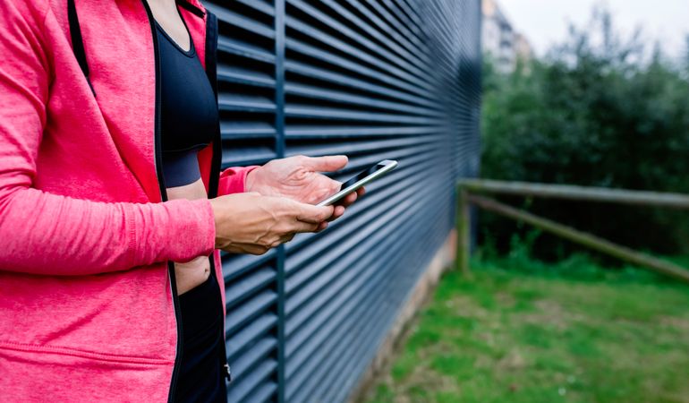 Unrecognizable female athlete with mobile phone