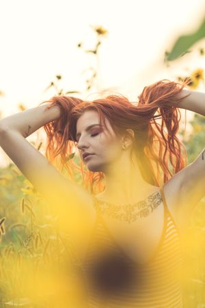 Woman raising her hair standing in yellow flower field