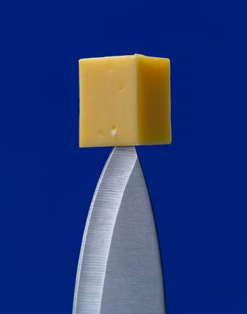 Cheese on tip of knife, close up, minimalist on a blue background