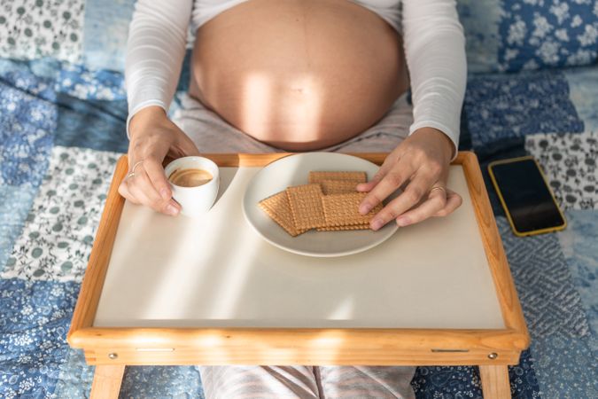 Tender pregnant woman having breakfast on bed