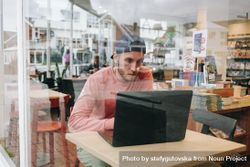 Man working in a cafe shot through glass 0JQeKb