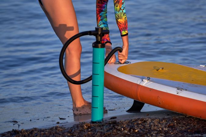 Unrecognizable woman with paddleboard and pump