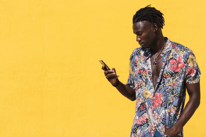 Stylish Black man in colorful shirt with smartphone