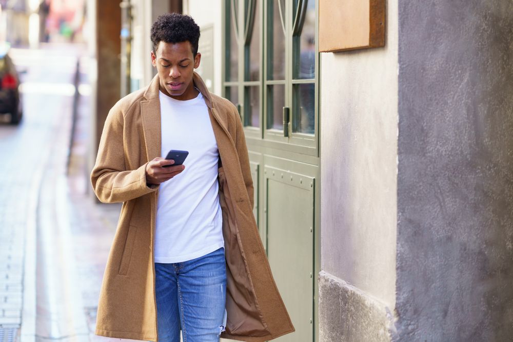 Cuban male looking down at his phone while walking