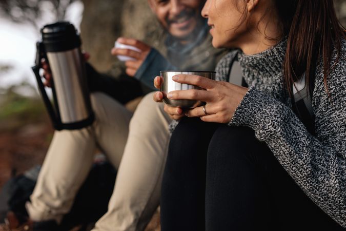 Cropped shot of couple hiking talking rest and drinking coffee