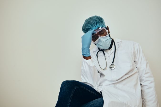 Stressed doctor in ppe gear with hand to his head