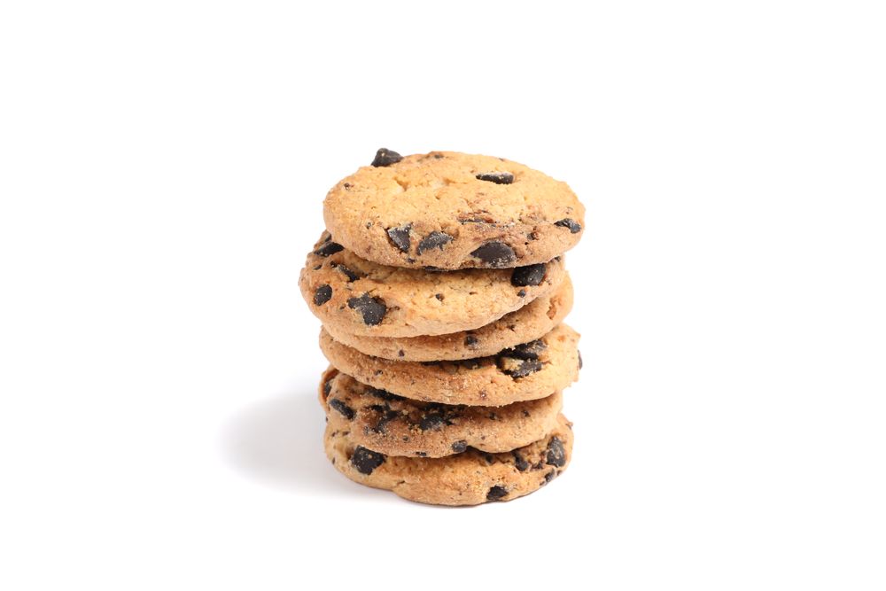 Stack of tasty chocolate chip cookies on plain background