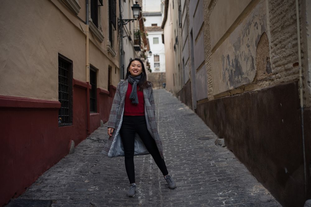Joyful Asian resting female hiking on old rocked narrow street