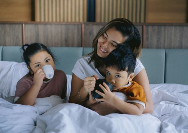 Mother enjoying her children's presence in bedroom in the morning