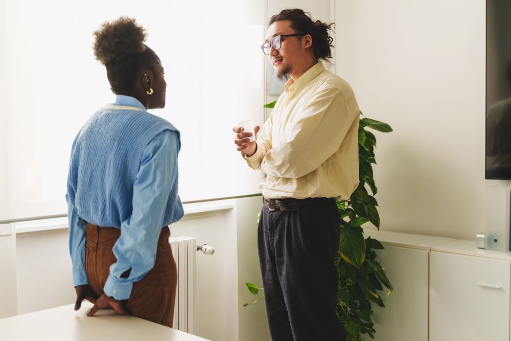 An Asian man and Black woman engage in a casual conversation in an office setting