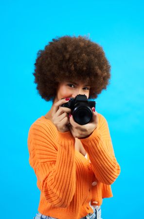 Portrait of a photographer covering her face with her camera while taking a picture
