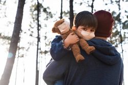 Man carrying a boy with facemask