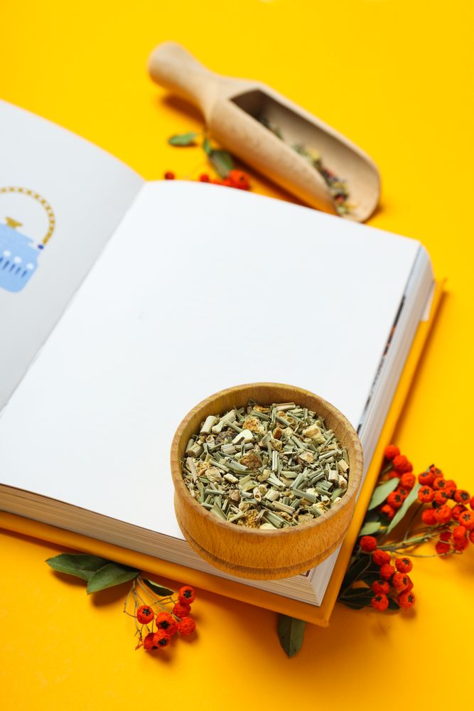 Alternative medicine: blank book and ingredients on yellow background
