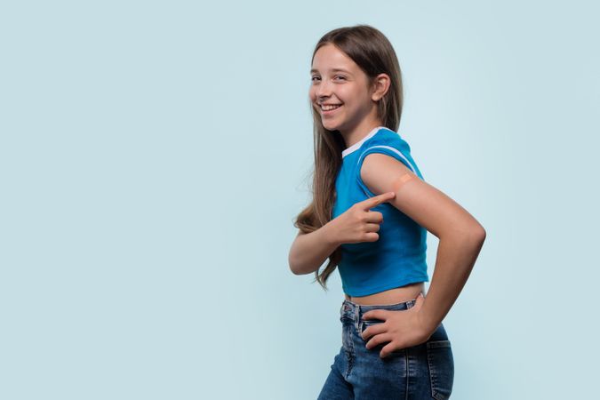 Young girl pointing at bandage on arm after vaccination