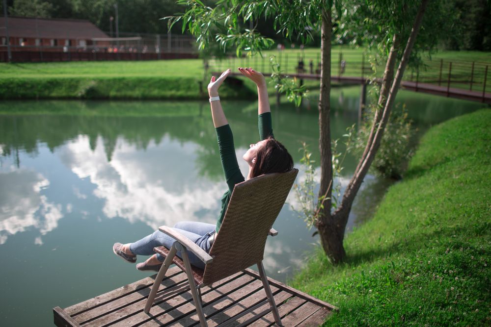 Woman sitting on chair on dock by river