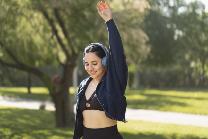 A woman performs exercise and shoulder and arm stretches in the park in the morning