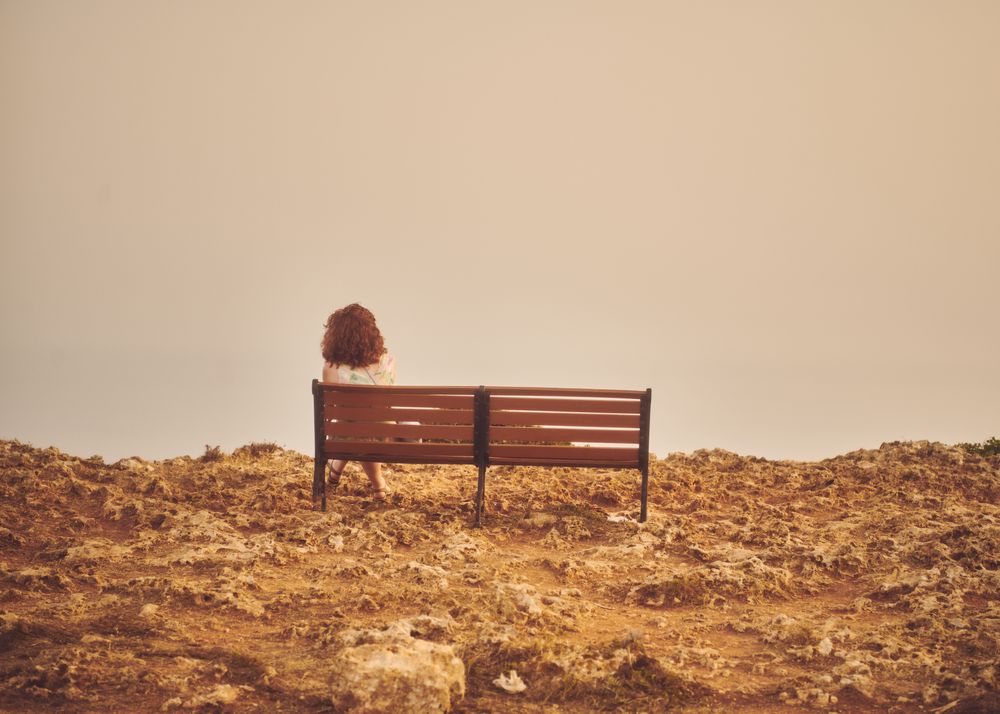 Back of woman sitting on bench enjoying view