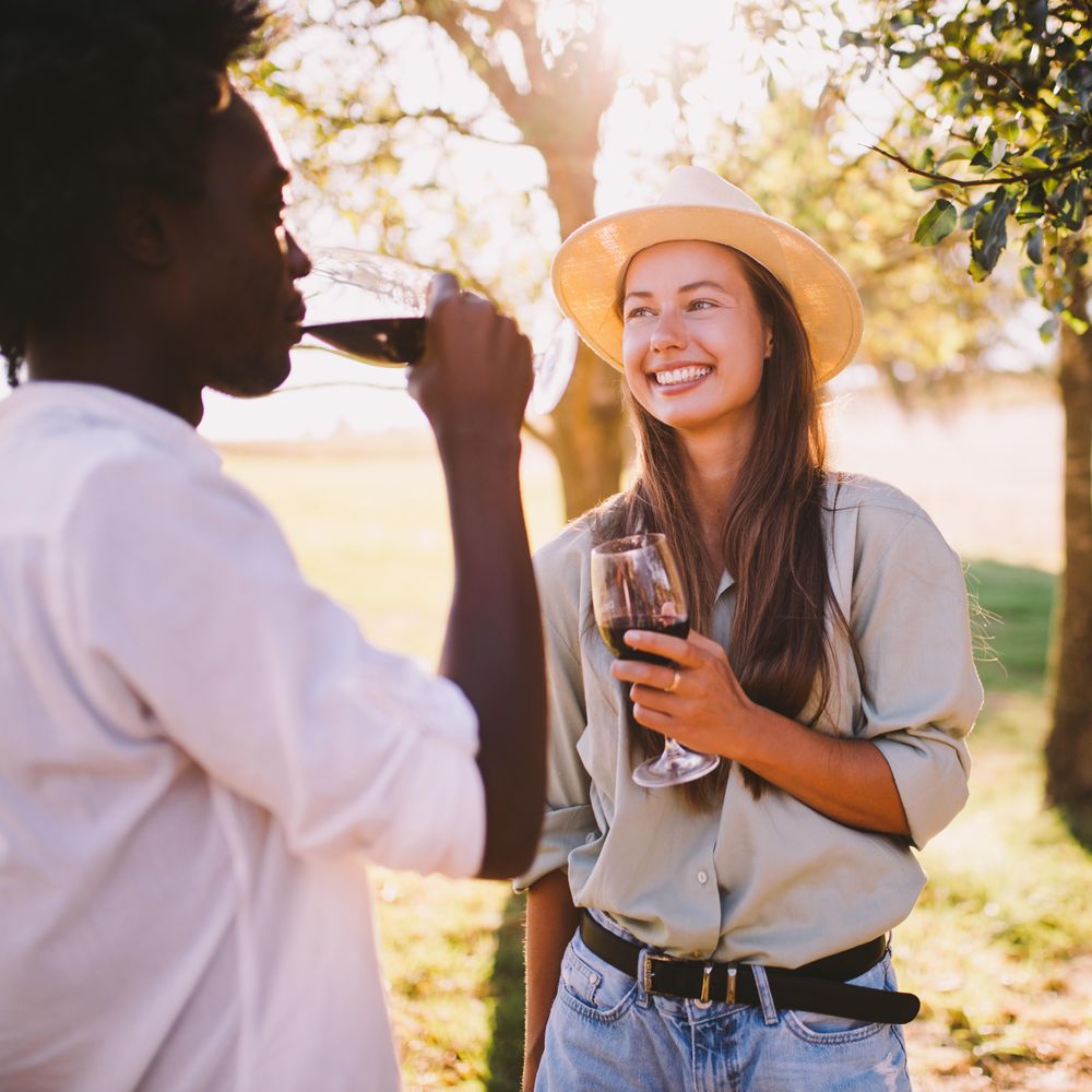 Man and woman smiling drinking red wine on a sunny day outdoors