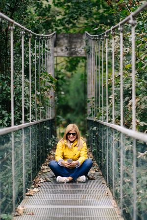 Happy female traveler taking selfie on suspension bridge in summer