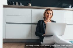 Woman sitting on floor in home with laptop 5zDBXb