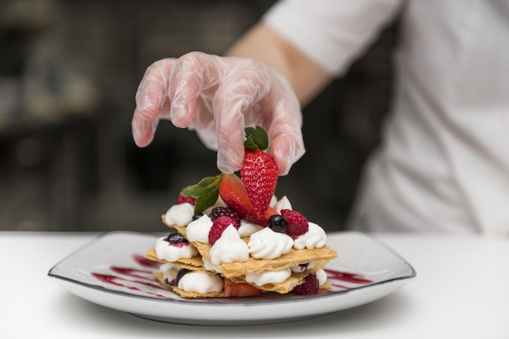 Chef putting strawberry on dessert