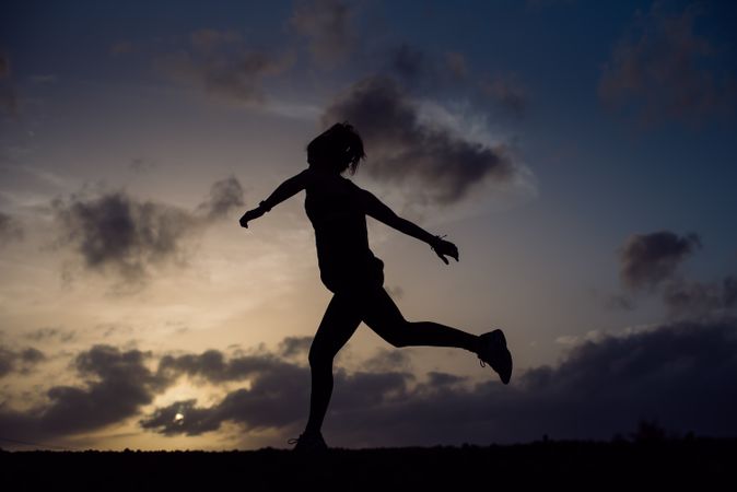 Jumping woman and sky with clouds at sunset